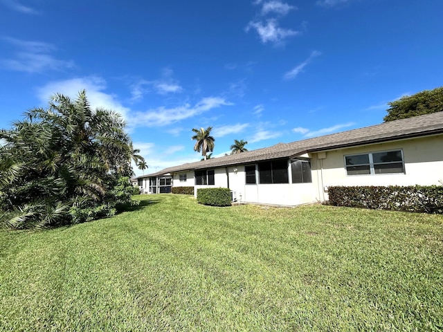 back of property with a lawn and stucco siding