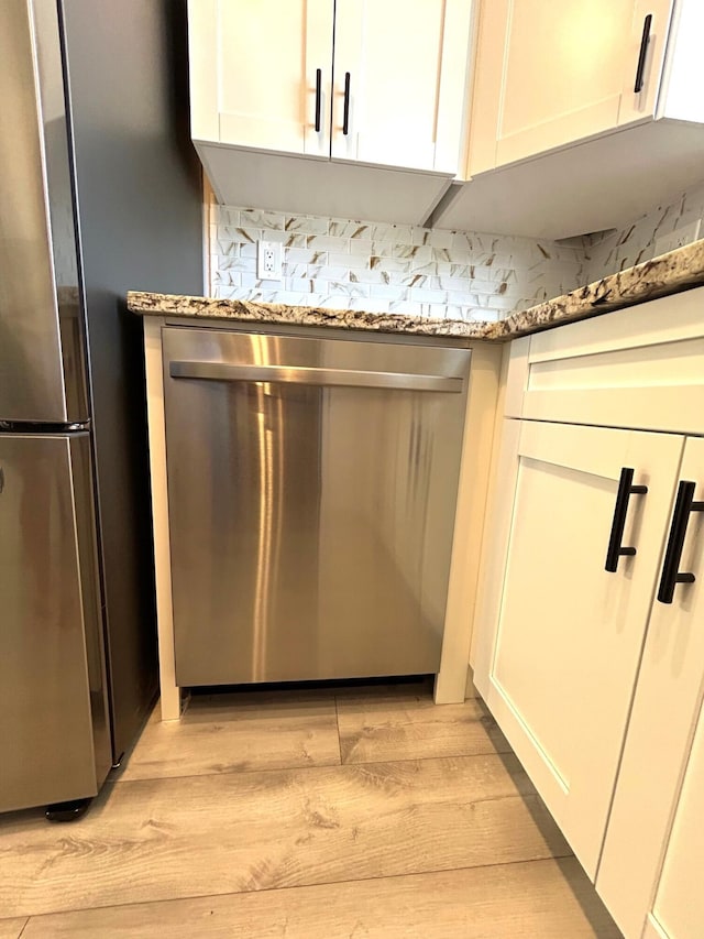 interior details with stone counters, light wood-style flooring, appliances with stainless steel finishes, and white cabinets