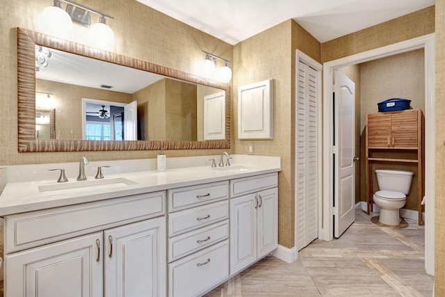bathroom with a ceiling fan, a sink, toilet, and double vanity