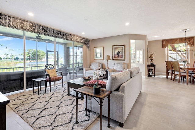 living room with ceiling fan with notable chandelier, baseboards, and recessed lighting