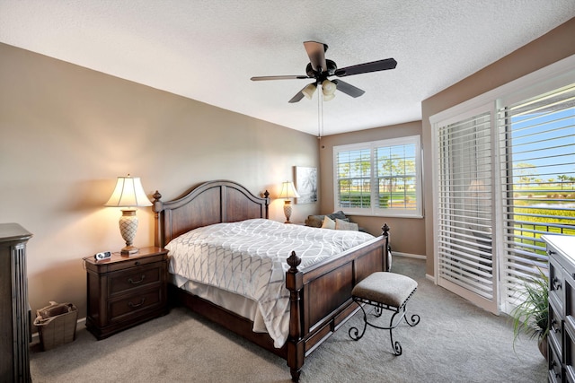 bedroom featuring light carpet, ceiling fan, a textured ceiling, and baseboards