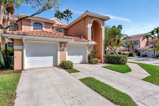 mediterranean / spanish house with driveway, an attached garage, a tile roof, and stucco siding