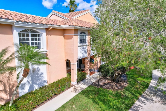 view of side of property with a tiled roof and stucco siding