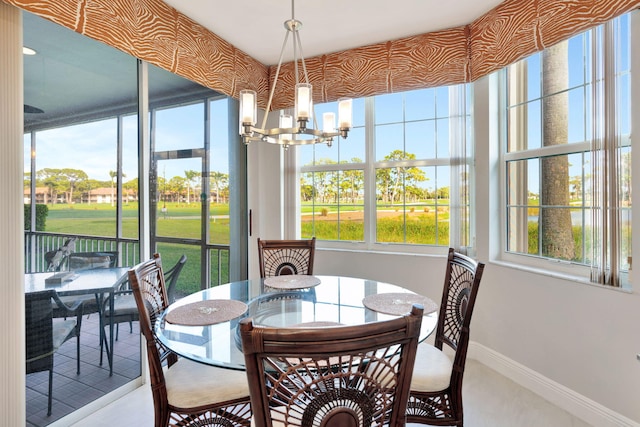 dining space featuring baseboards, a sunroom, a wealth of natural light, and an inviting chandelier