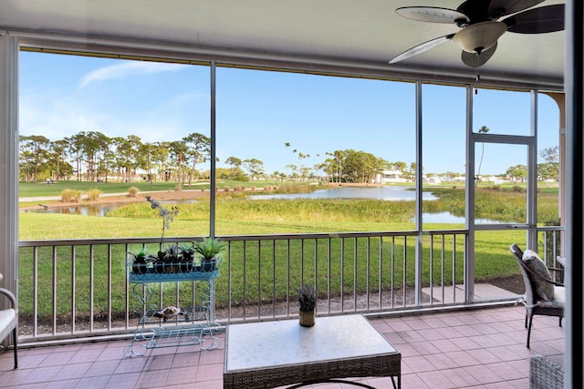 unfurnished sunroom with ceiling fan, a water view, and a healthy amount of sunlight