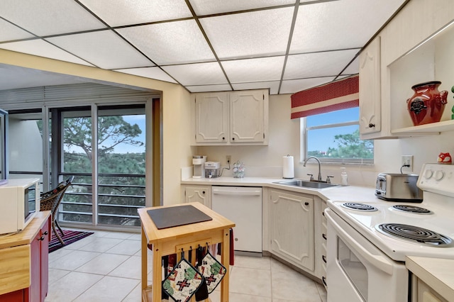 kitchen with a paneled ceiling, white appliances, a sink, light countertops, and open shelves