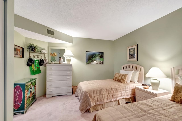 bedroom featuring light carpet, a textured ceiling, and visible vents