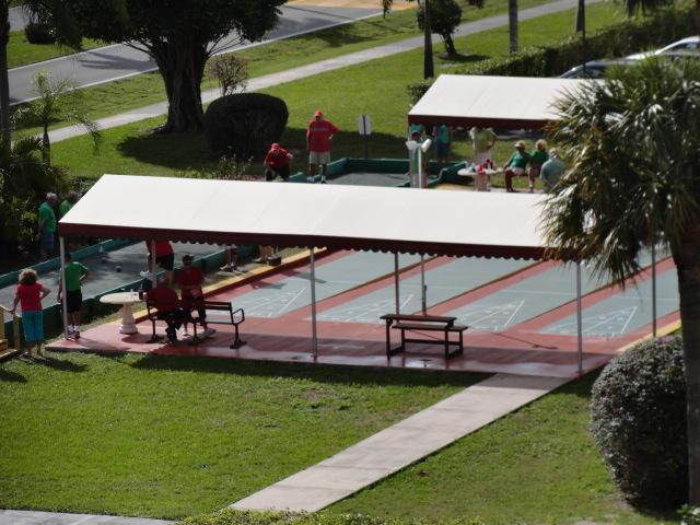 view of community featuring shuffleboard and a lawn