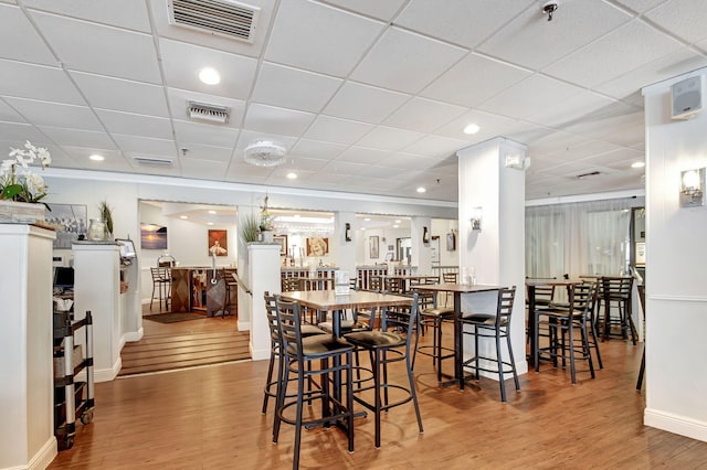 dining space with light wood-style floors, a paneled ceiling, visible vents, and baseboards