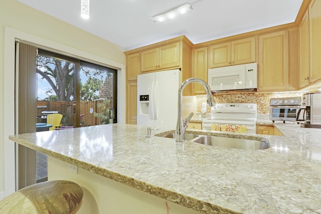 kitchen with white appliances, decorative backsplash, light stone counters, light brown cabinetry, and a sink