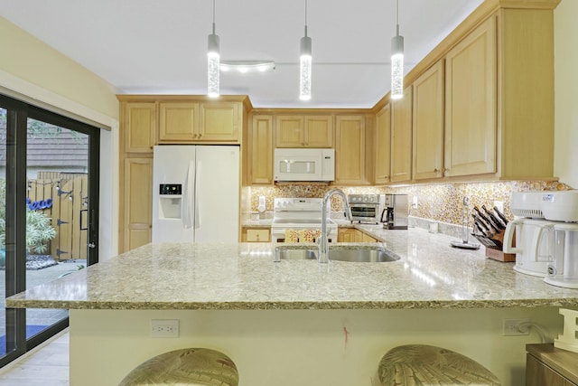 kitchen with white appliances, a peninsula, a sink, light stone countertops, and backsplash