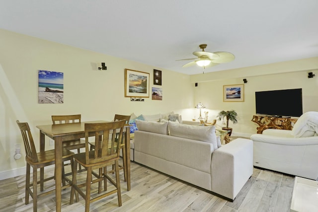 living area with light wood-type flooring, ceiling fan, and baseboards