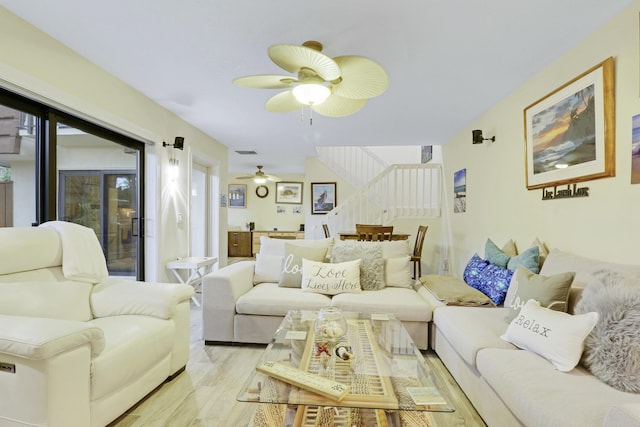 living room featuring light wood-type flooring, visible vents, and a ceiling fan