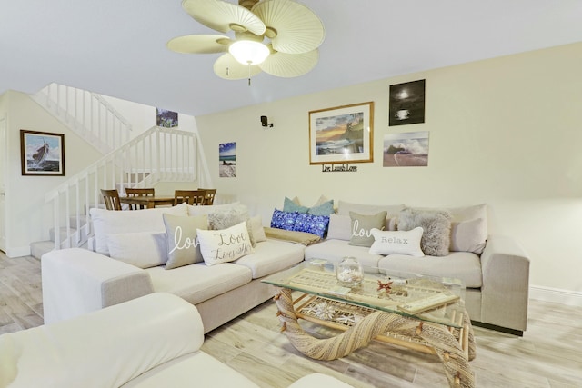 living area with a ceiling fan, baseboards, stairway, and wood finished floors