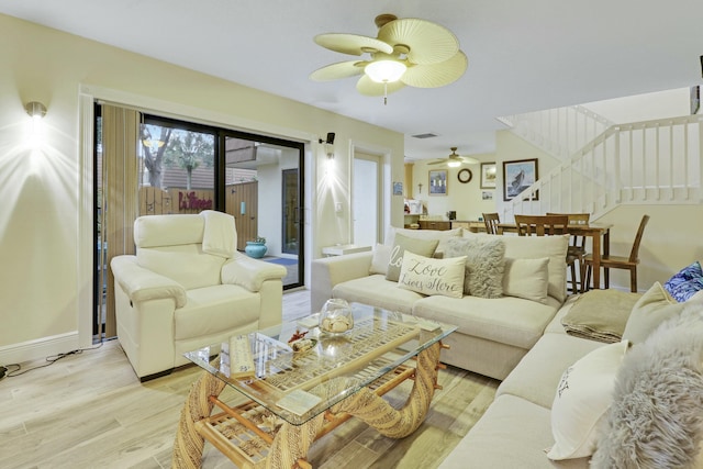 living room with light wood-style flooring, baseboards, and ceiling fan