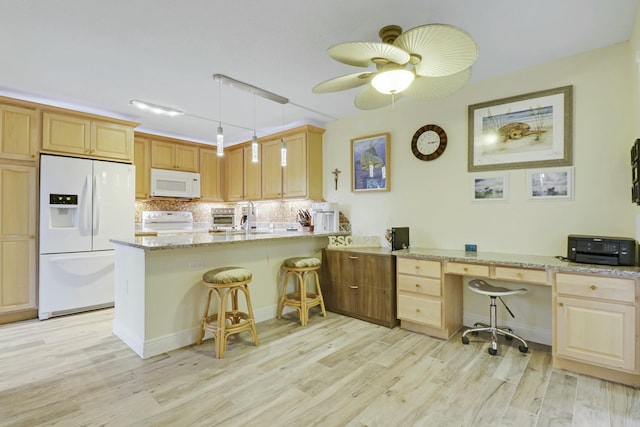 kitchen with a peninsula, white appliances, decorative backsplash, and light wood-style floors