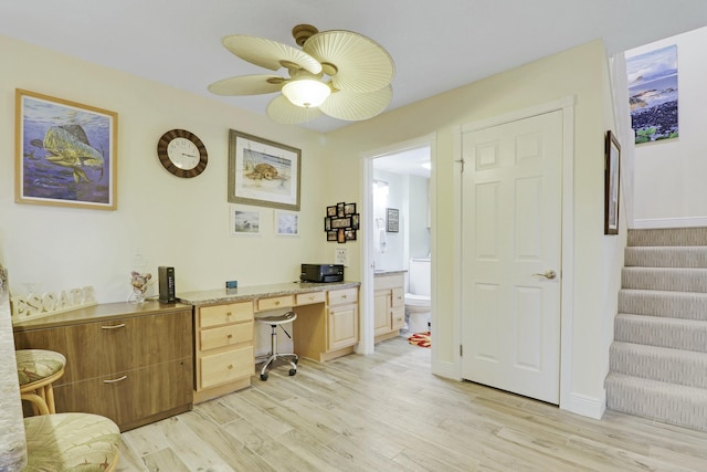 office with light wood finished floors, ceiling fan, baseboards, and built in desk