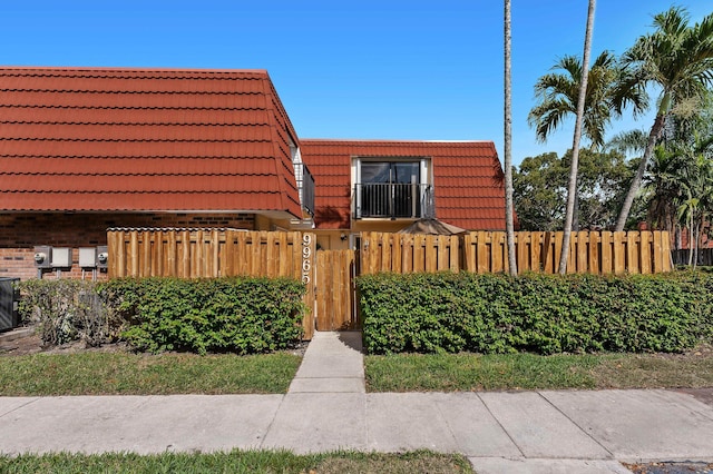 view of property with a fenced front yard, a tile roof, mansard roof, and brick siding