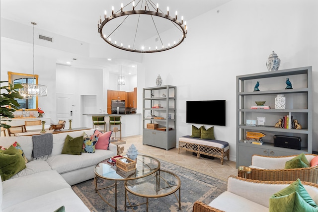 living room with light tile patterned floors, visible vents, a towering ceiling, and an inviting chandelier