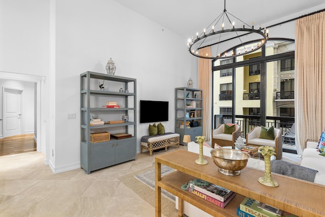 living room with a fireplace, light tile patterned floors, a towering ceiling, a chandelier, and baseboards