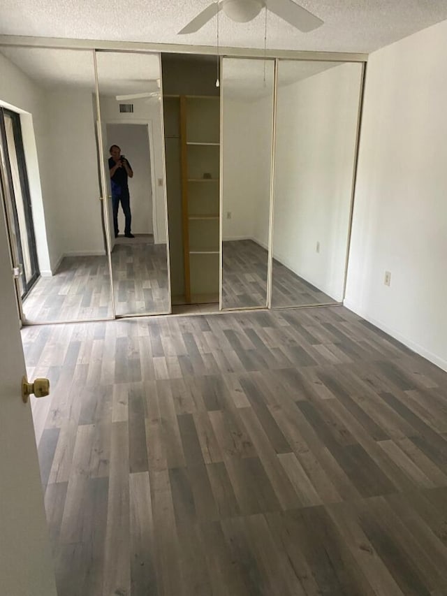 unfurnished bedroom with ceiling fan, a textured ceiling, visible vents, and dark wood-style flooring