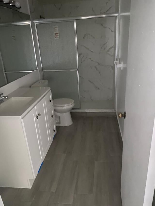 full bathroom featuring a marble finish shower, vanity, toilet, and wood finished floors