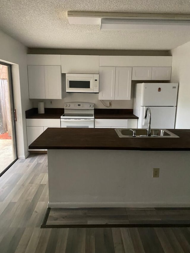 kitchen featuring white appliances, dark countertops, and white cabinets