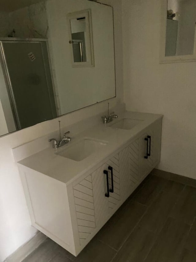 bathroom featuring double vanity, baseboards, a sink, and wood finished floors