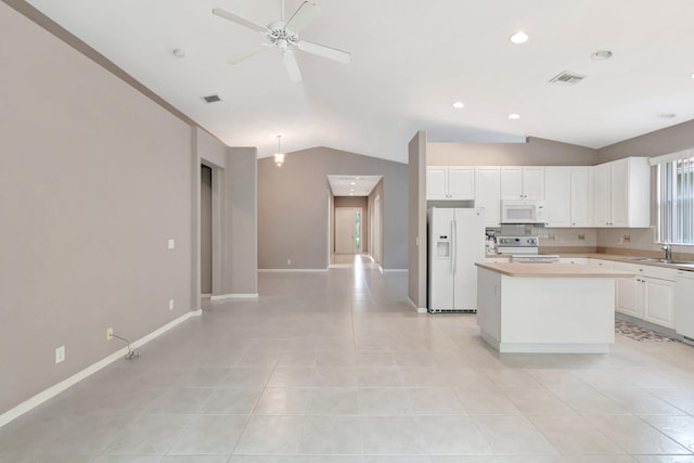 kitchen featuring lofted ceiling, light countertops, visible vents, a kitchen island, and white appliances