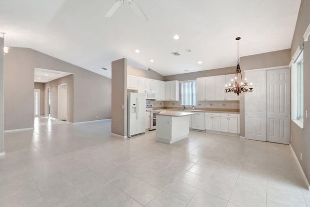 kitchen featuring lofted ceiling, white appliances, white cabinetry, and a center island