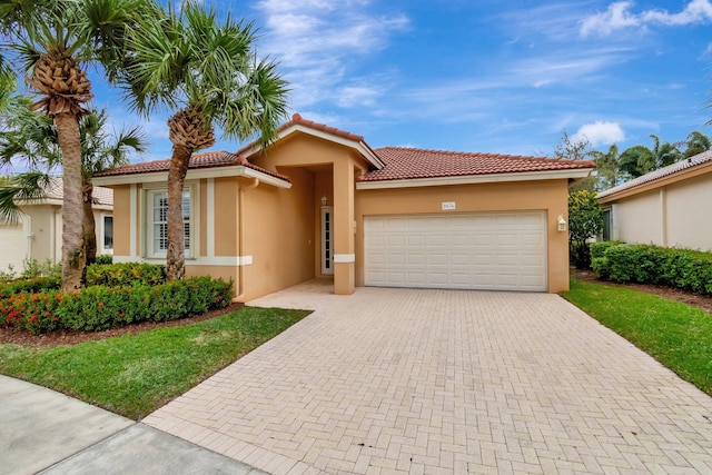 mediterranean / spanish house with a garage, decorative driveway, a tiled roof, and stucco siding