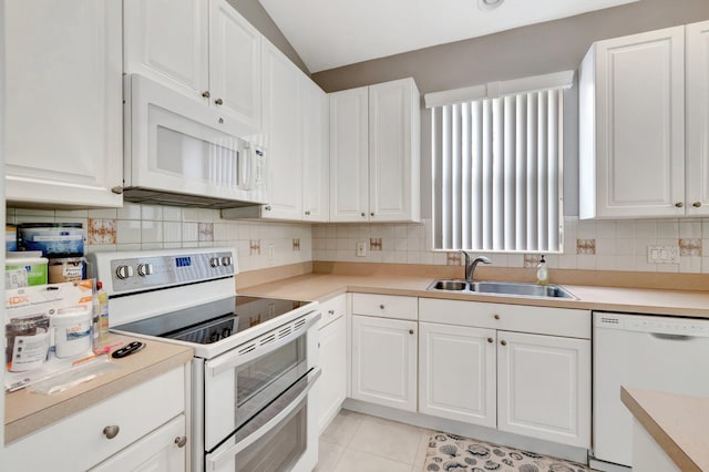 kitchen with white appliances, white cabinets, and a sink