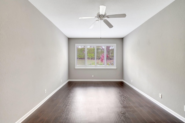 spare room with ceiling fan, baseboards, and dark wood-type flooring