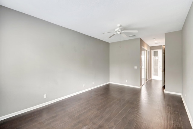 empty room with ceiling fan, dark wood-type flooring, visible vents, and baseboards