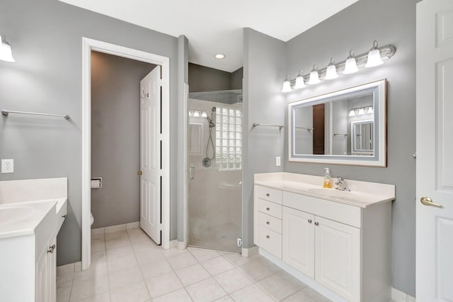 full bath with a sink, two vanities, and a shower stall