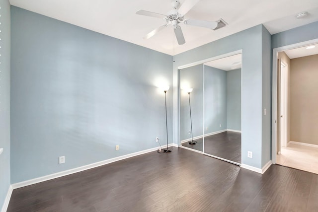 unfurnished bedroom with ceiling fan, a closet, dark wood finished floors, and baseboards