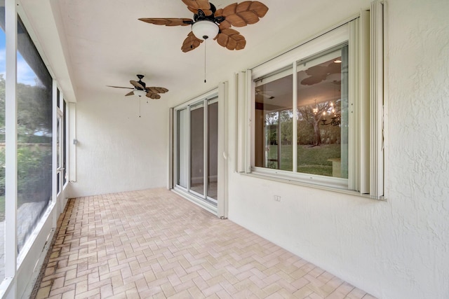 unfurnished sunroom with ceiling fan