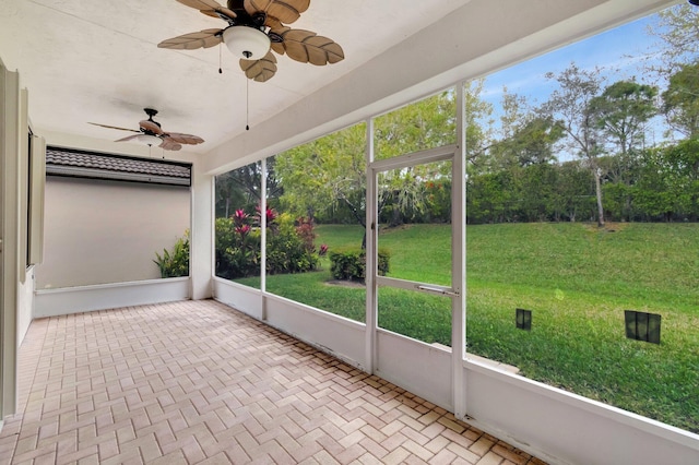 unfurnished sunroom featuring a ceiling fan and a wealth of natural light