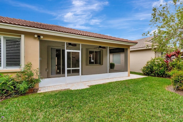 back of property featuring ceiling fan, a sunroom, a yard, and stucco siding