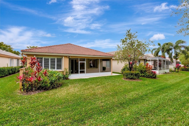 back of property with stucco siding, a tiled roof, and a yard