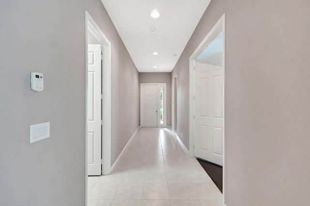 hall featuring recessed lighting, baseboards, and light tile patterned floors