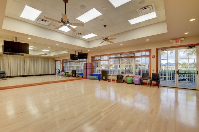 workout room featuring a tray ceiling, wood finished floors, and visible vents