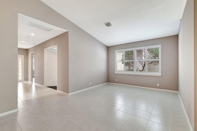 spare room with vaulted ceiling, light tile patterned flooring, visible vents, and baseboards