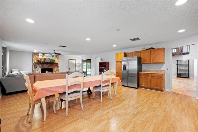 dining space featuring a fireplace, recessed lighting, visible vents, light wood-style floors, and a textured ceiling