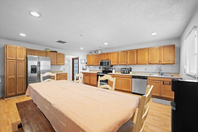 kitchen with recessed lighting, light countertops, appliances with stainless steel finishes, light wood-style floors, and a sink