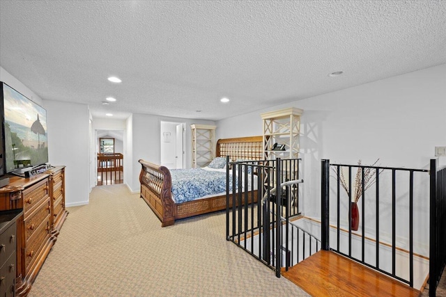 bedroom with a textured ceiling, recessed lighting, and light colored carpet