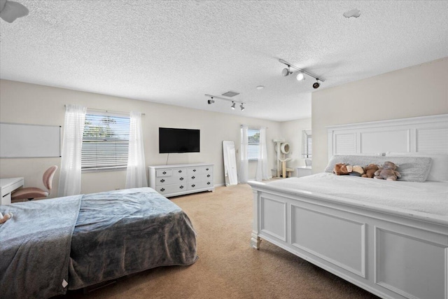 carpeted bedroom with a textured ceiling, visible vents, and track lighting