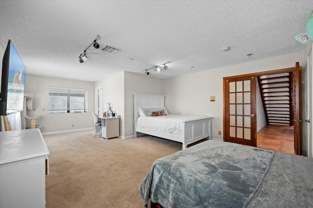 bedroom featuring carpet floors, visible vents, a textured ceiling, track lighting, and baseboards