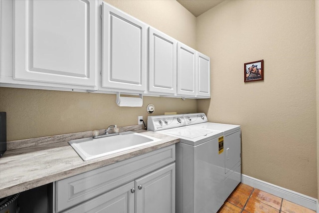 washroom featuring light tile patterned floors, cabinet space, a sink, separate washer and dryer, and baseboards