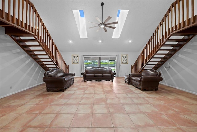 unfurnished living room featuring light tile patterned floors, a textured ceiling, a skylight, baseboards, and stairway